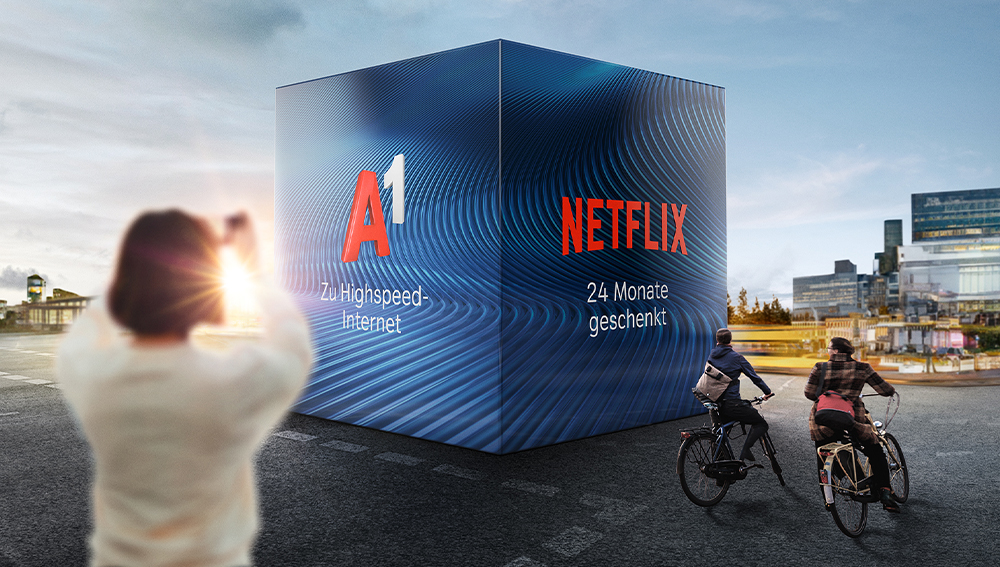 Frau fotografiert einen großen blauen Würfel mit Angebot von A1 und Netflix
