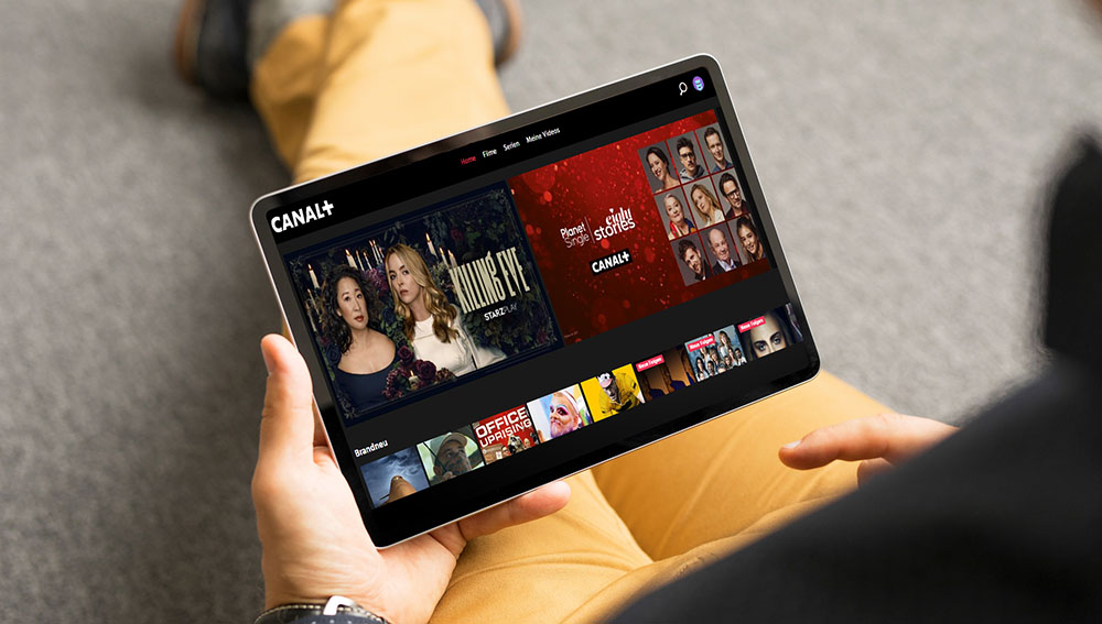Mann mit Tablet auf dem das Interface von CANAL+ zu sehen ist
