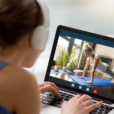 Frau mit Kopfhörern startet ein Home Workout am Laptop