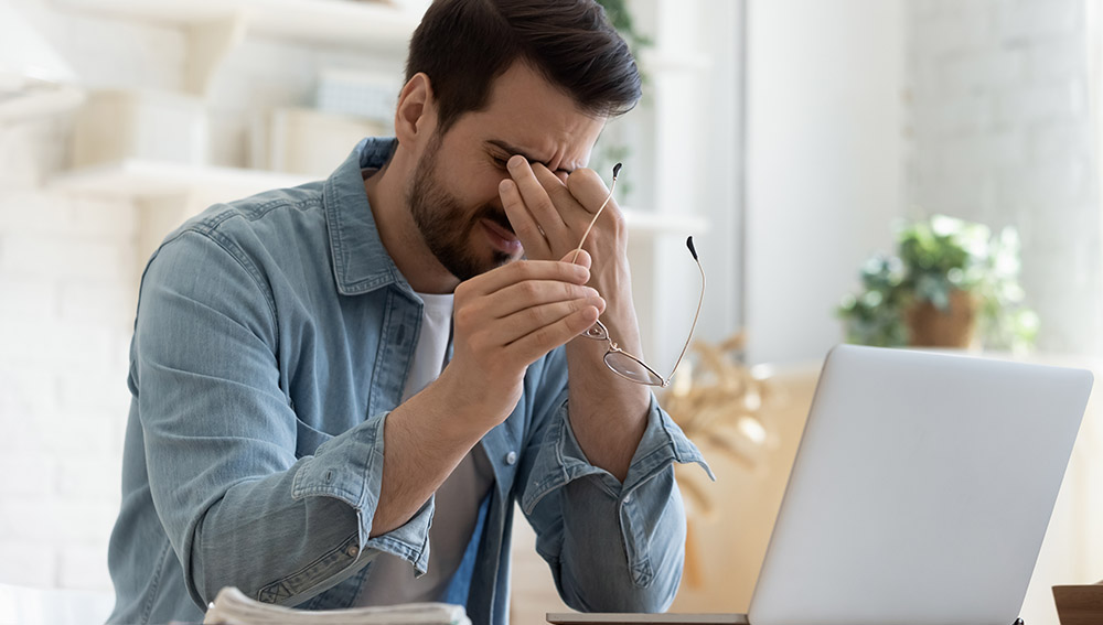 Mann sitzt mit verzweifeltem Gesichtsausdruck vor Laptop