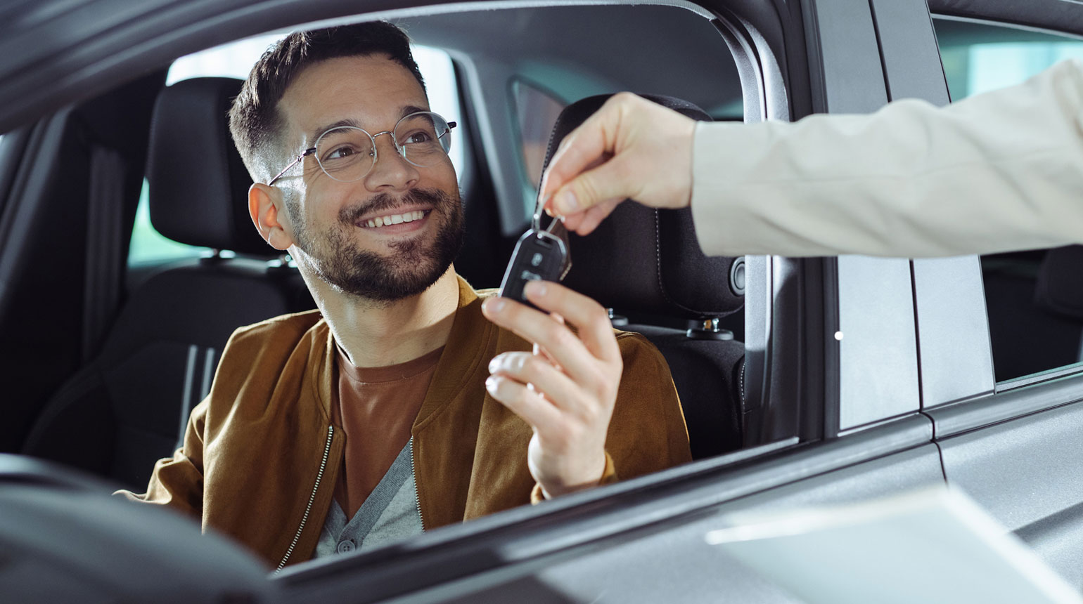Mann im Auto bekommt Autoschlüssel überreicht