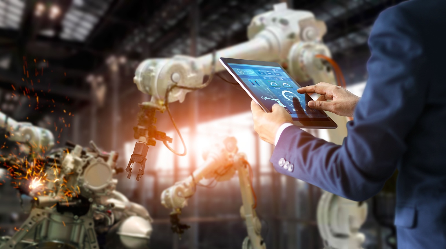 Eine Person steht vor einem Roboter und hält ein Tablet in der Hand.