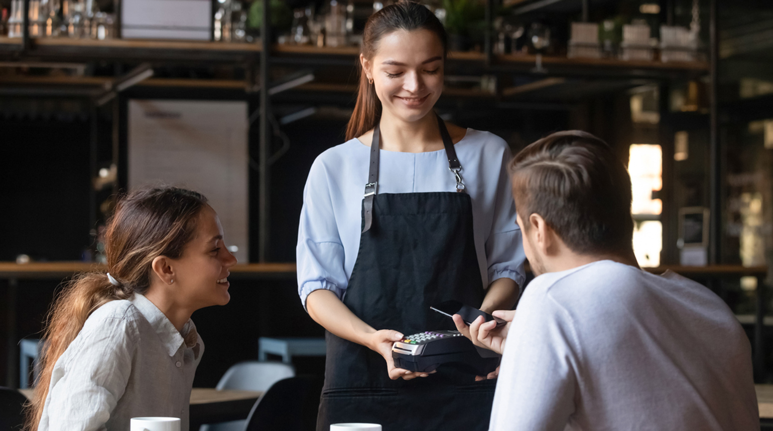 Pärchen im Café bezahlt kontaktlos mit Karte