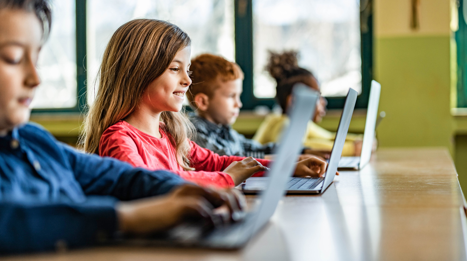 Kinder in der Schule mit Laptops auf dem Tisch