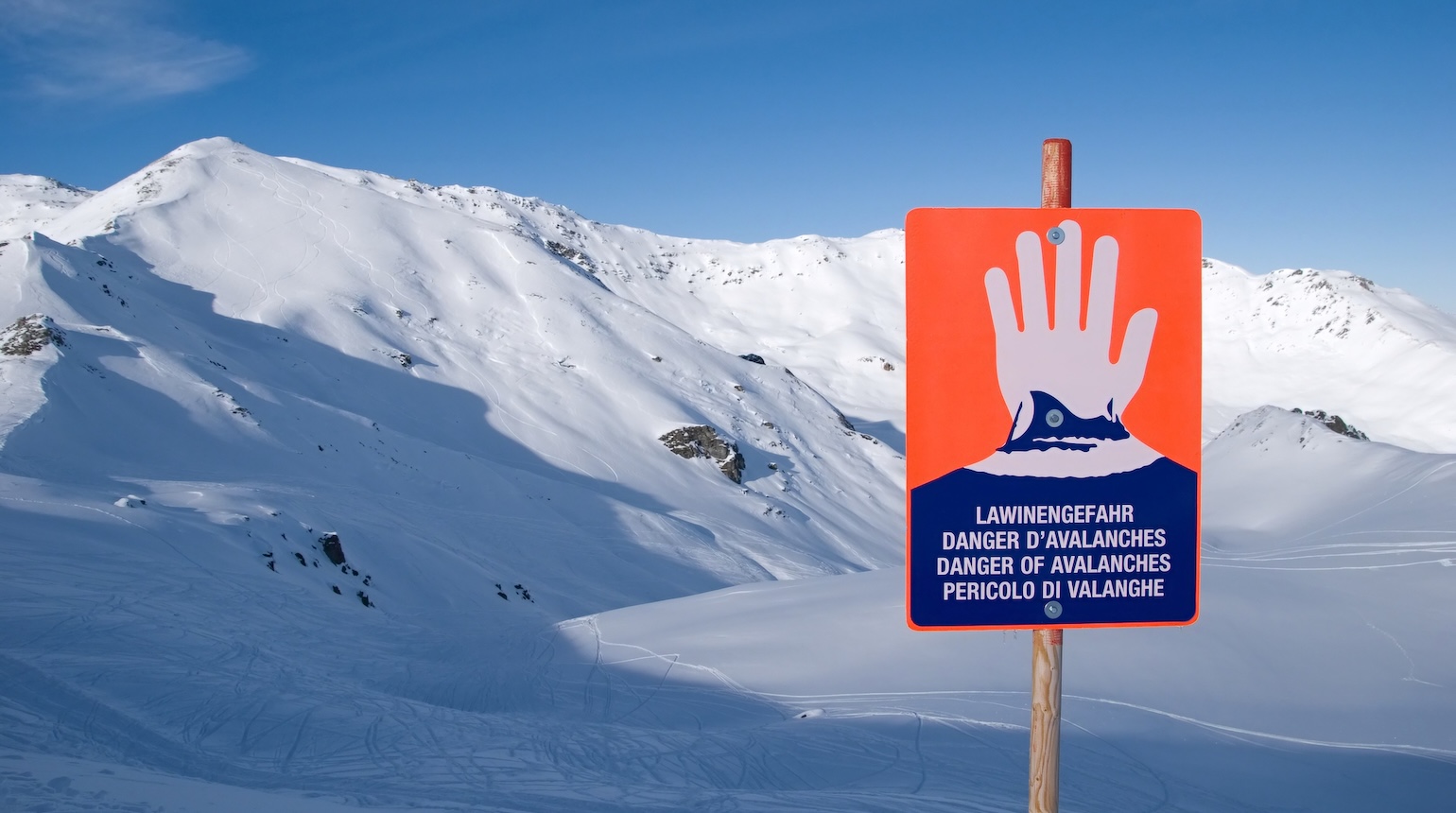 Lawinenwarnschild und im Hintergrund Schneeberge