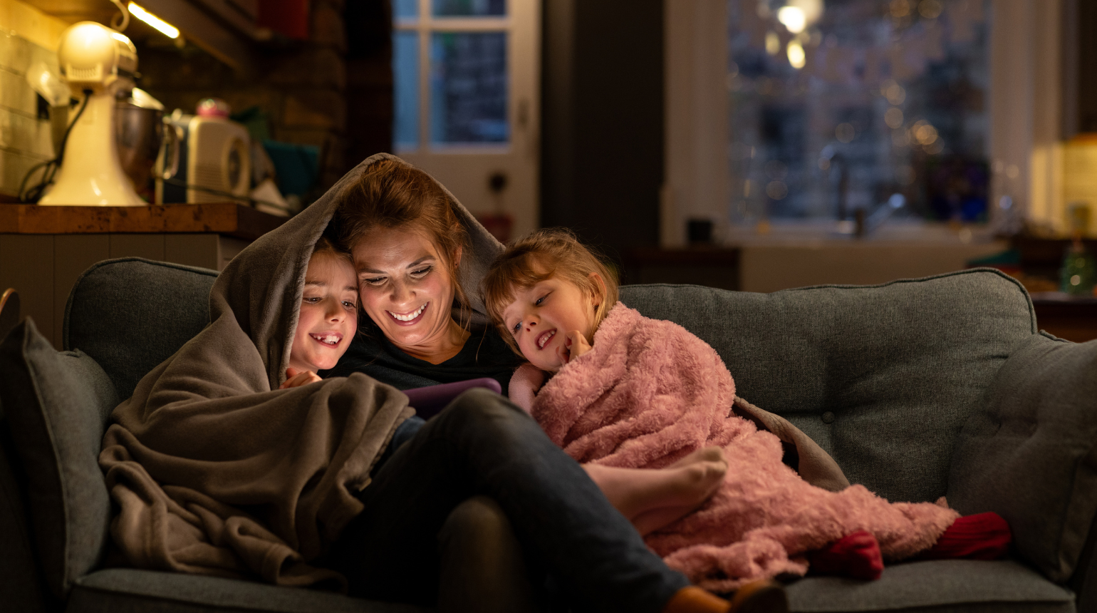Mutter mit 2 Kindern entspannt auf der Couch