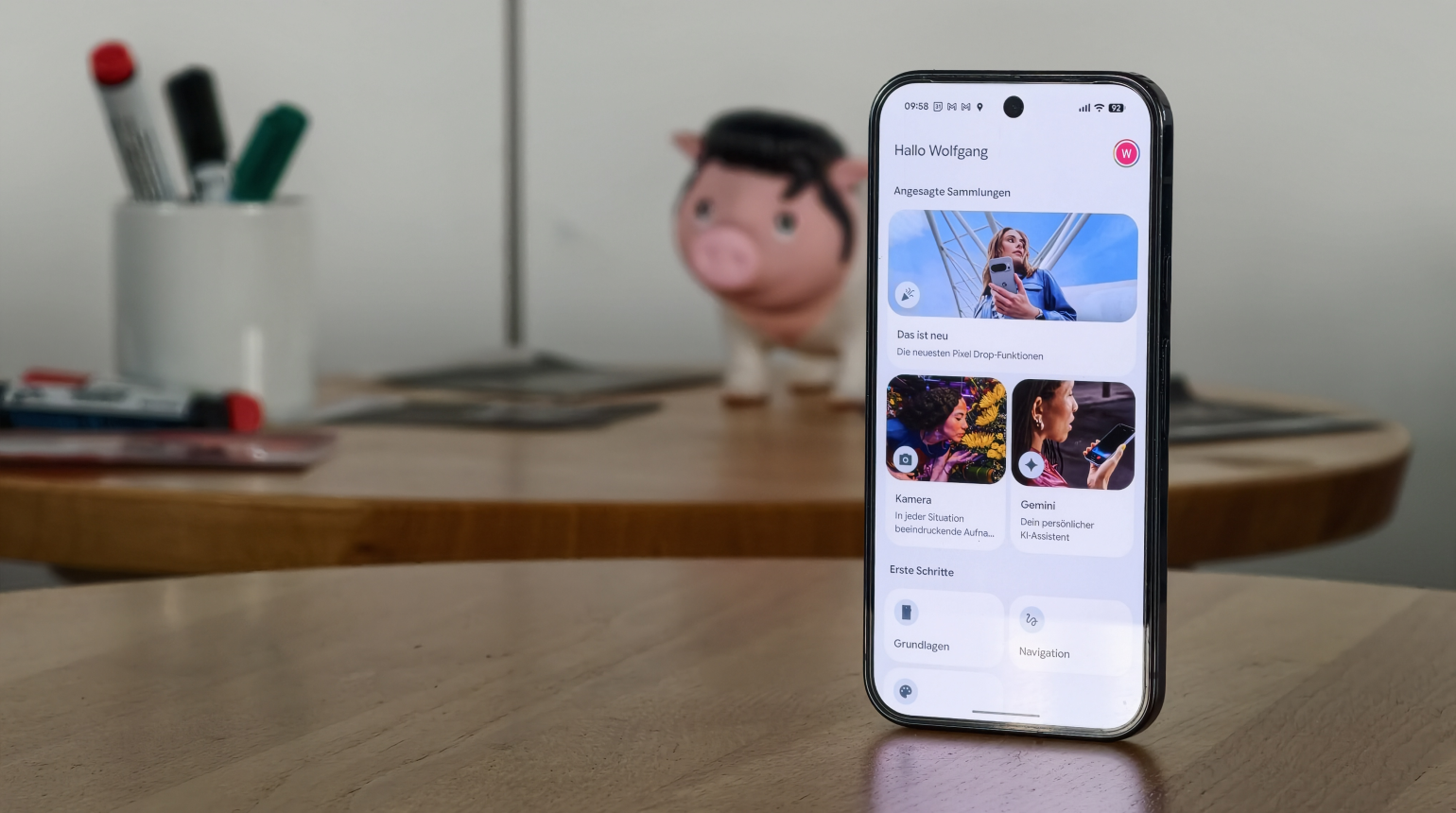 Smartphone auf Holztisch zeigt Startseite mit Begrüßung