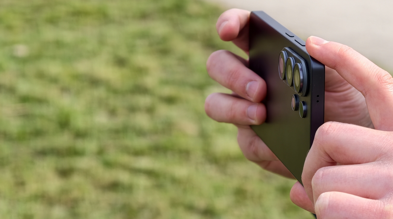 Person hält ein Smartphone quer, bereit ein Foto zu machen, im Hintergrund