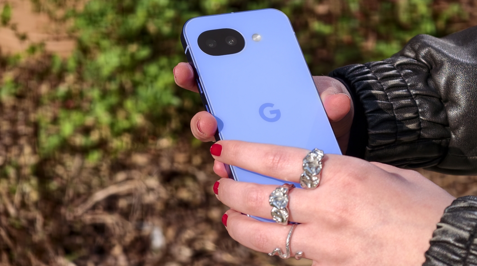 Hand hält ein hellblaues Google Pixel Smartphone, Hintergrund unscharf, rot