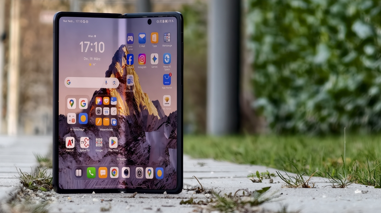 Aufgeklapptes faltbares Smartphone mit Bergmotiv auf dem Display, viele App
